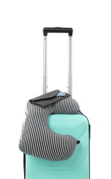 Photo of Soft travel pillow and purse on turquoise suitcase isolated on white