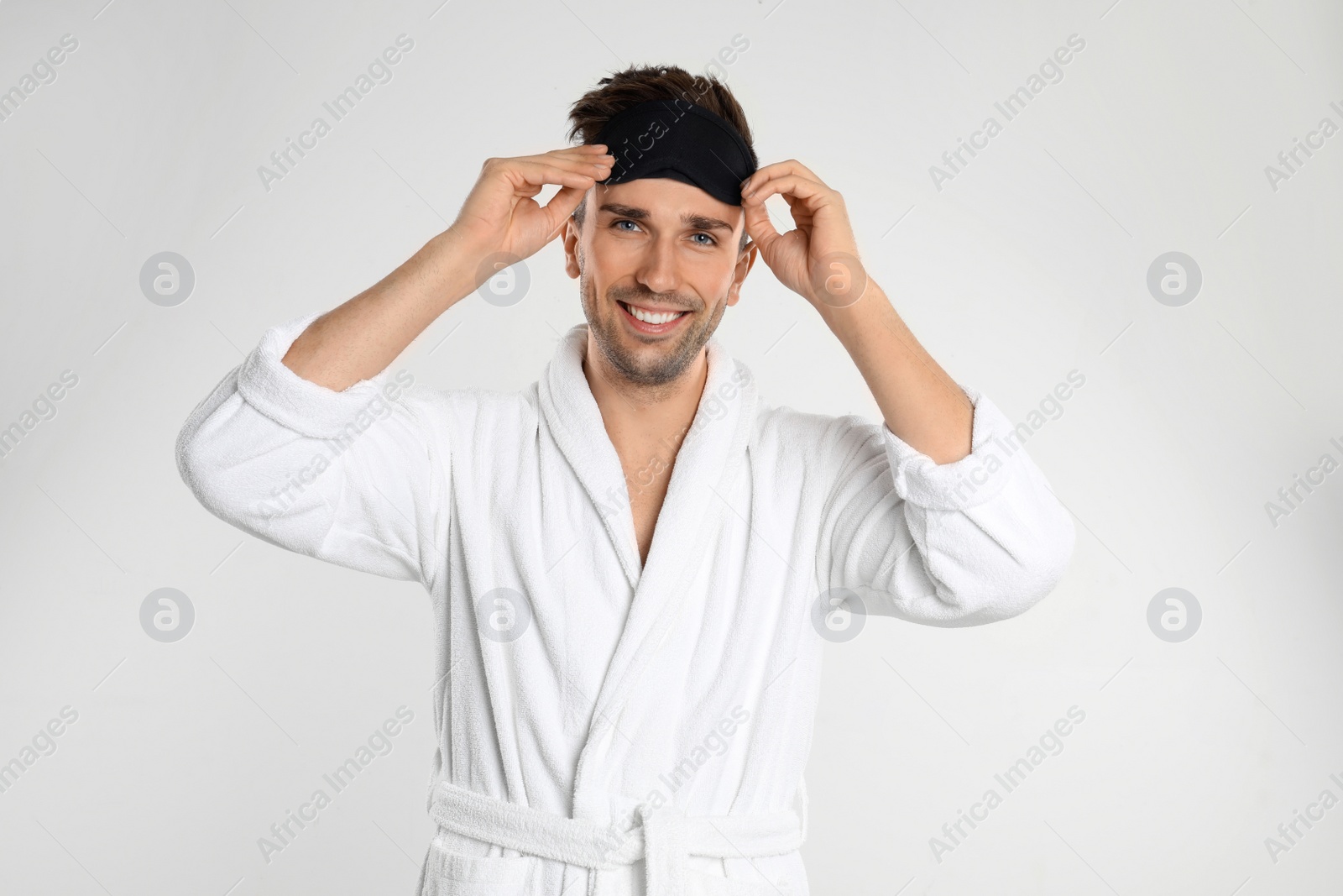 Photo of Happy young man in bathrobe on white background