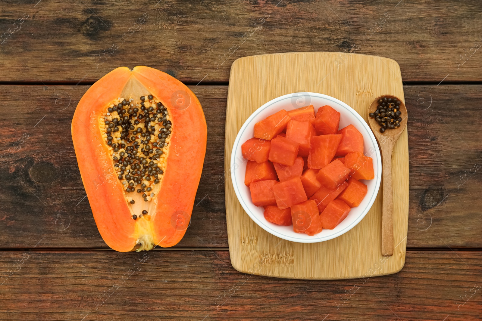 Photo of Tasty cut papaya fruits on wooden table, flat lay