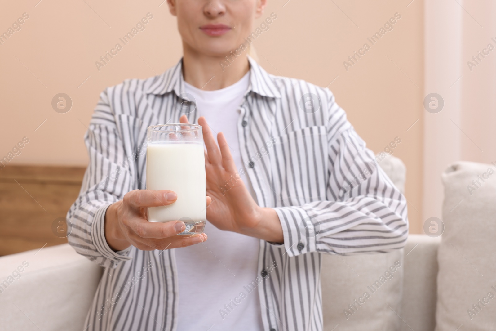 Photo of Woman with glass of milk suffering from lactose intolerance at home, closeup