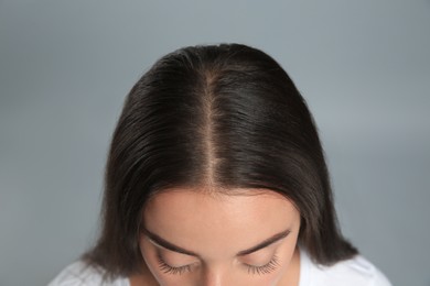 Photo of Woman with hair loss problem on grey background, above view. Trichology treatment