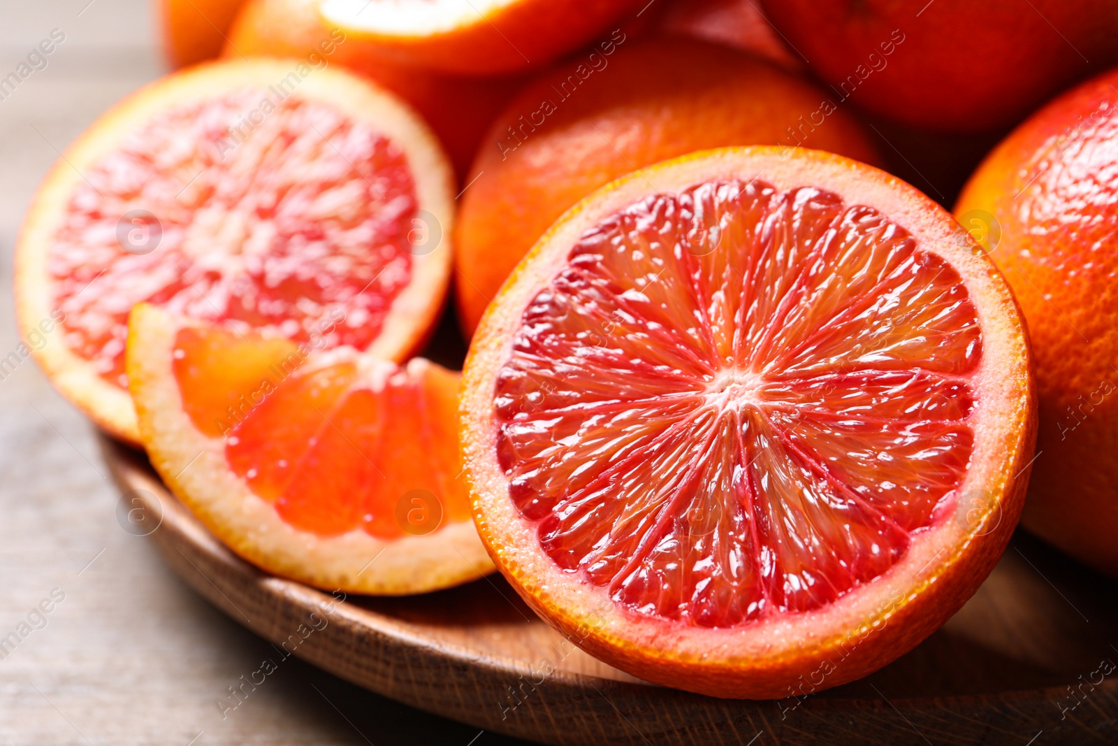 Photo of Whole and cut red oranges on wooden table, closeup