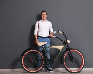 Portrait of handsome young man with bicycle near color wall