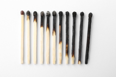 Photo of Row of burnt matches and whole one on white background, top view. Human life phases concept