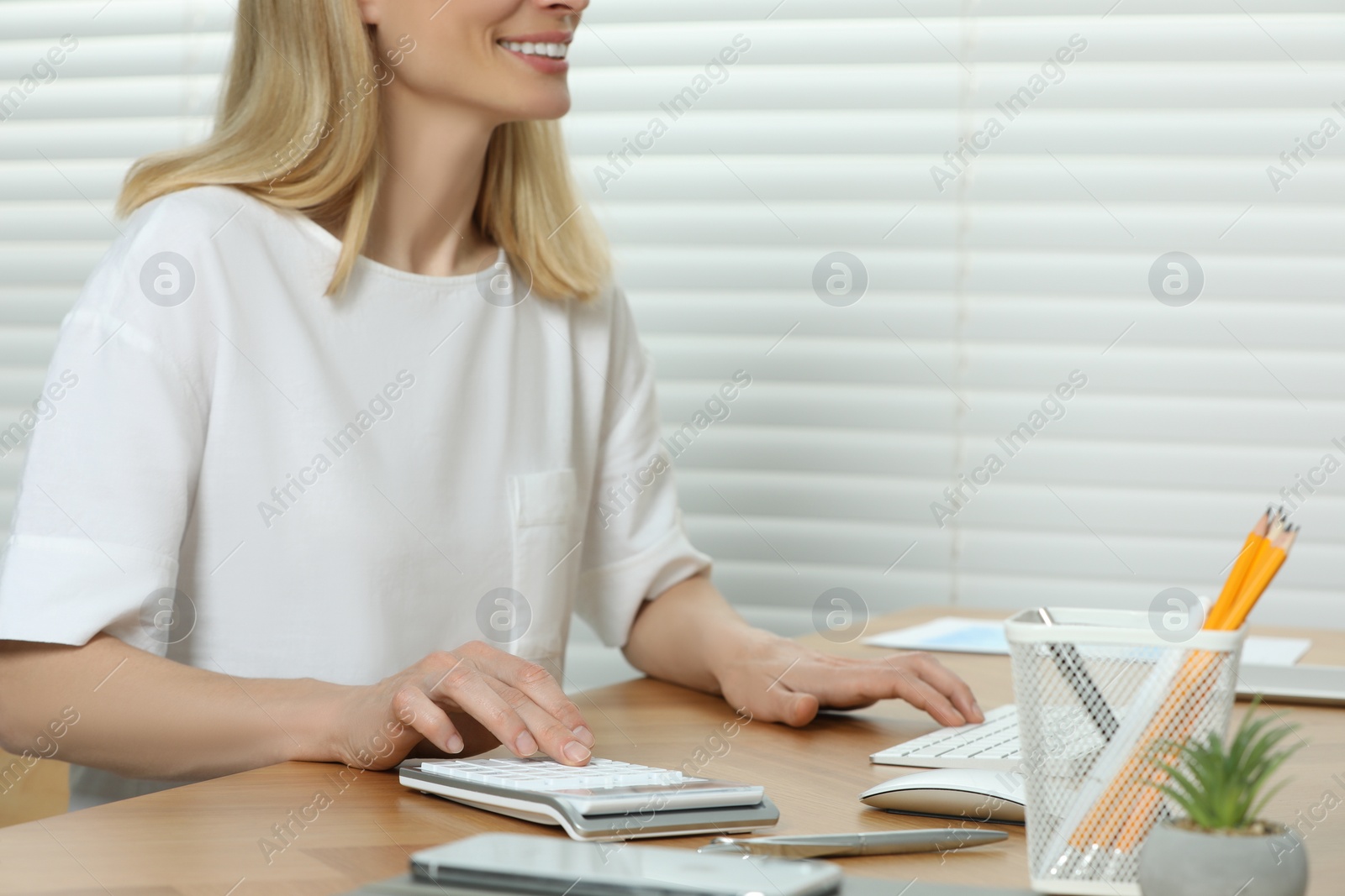 Photo of Professional accountant using calculator at wooden desk in office, closeup