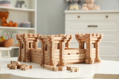 Wooden fortress and building blocks on white table indoors. Children's toy