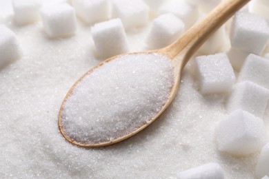 Photo of Different types of white sugar and spoon as background, closeup