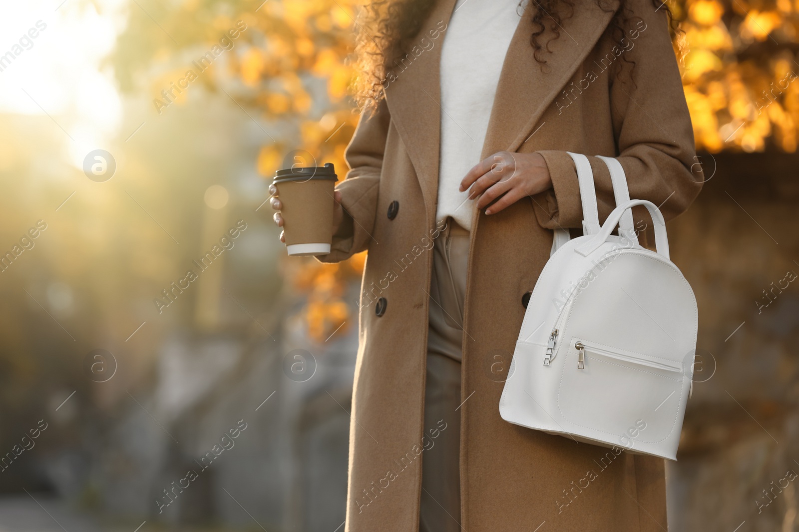 Photo of Young woman with stylish white backpack and hot drink outdoors on sunny day, closeup