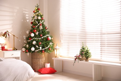 Photo of Beautiful decorated Christmas tree in bedroom interior, space for text