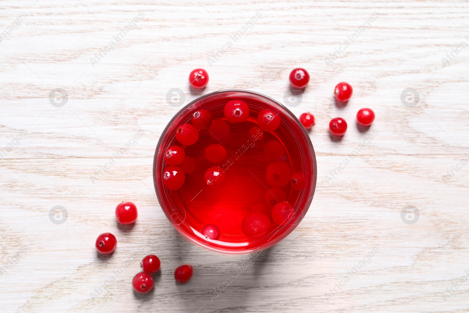 Photo of Tasty cranberry juice in glass and fresh berries on white wooden table, flat lay