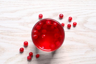 Photo of Tasty cranberry juice in glass and fresh berries on white wooden table, flat lay