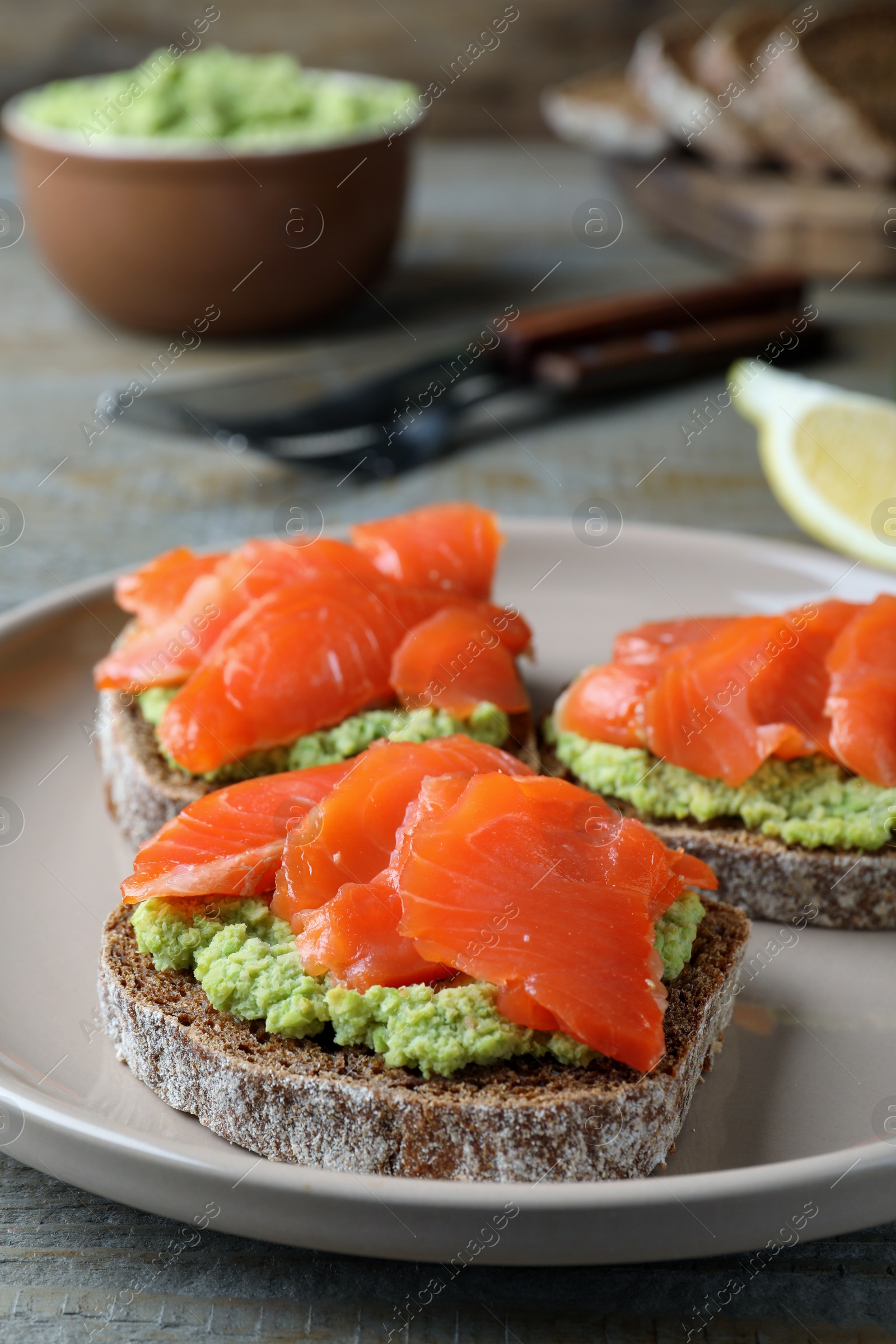 Photo of Delicious sandwiches with salmon and avocado on grey plate, closeup
