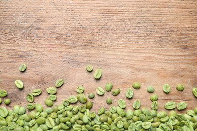 Photo of Many green coffee beans on wooden table, flat lay. Space for text