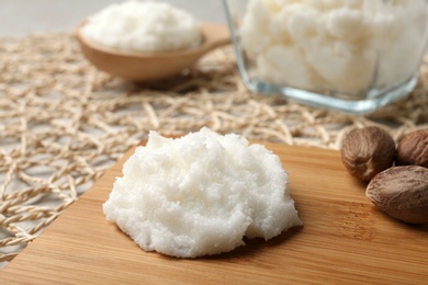 Shea butter and nuts on wooden board, closeup