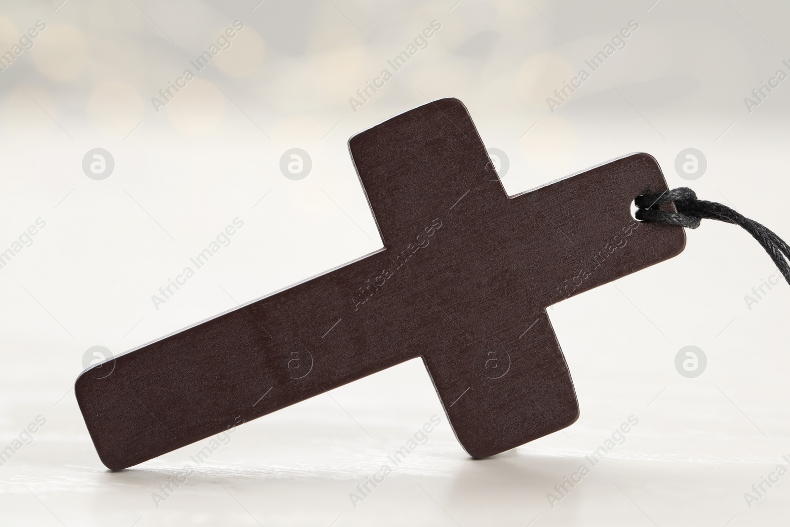 Photo of Christian cross on white wooden table, closeup