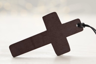 Photo of Christian cross on white wooden table, closeup