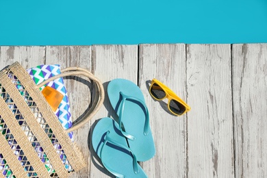 Beach accessories on wooden deck near outdoor swimming pool, flat lay. Space for text