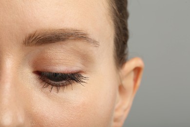 Photo of Woman with long eyelashes after mascara applying against grey background, closeup