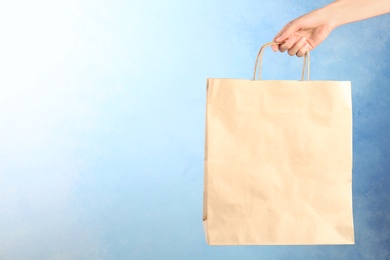 Photo of Woman holding paper shopping bag on color background