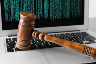 Photo of Modern laptop and wooden gavel on table, closeup. Cyber crime