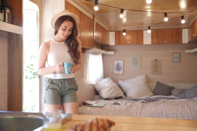 Photo of Young woman with cup in trailer, space for text. Camping vacation