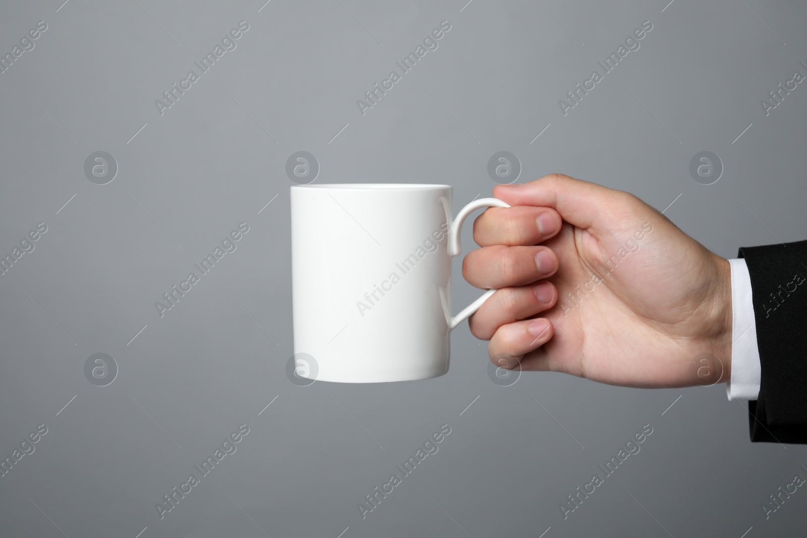 Photo of Man holding white mug on gray background, closeup. Space for text