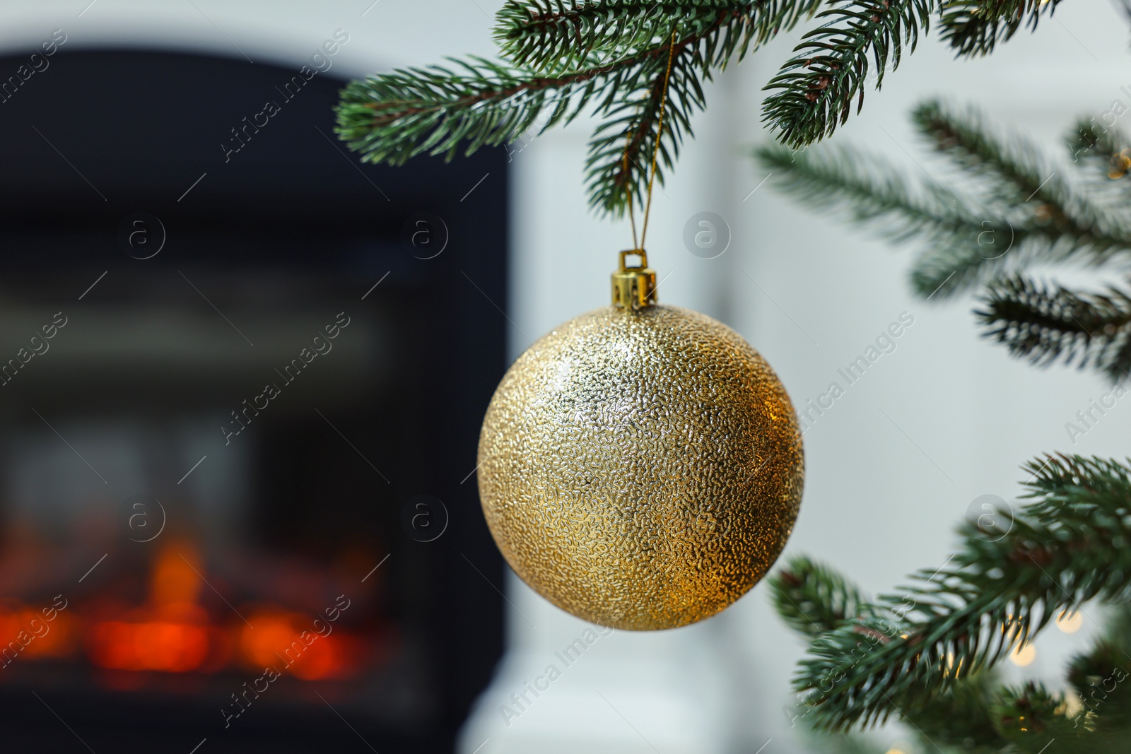 Photo of Beautiful Christmas bauble hanging on fir tree branch in room, closeup. Space for text