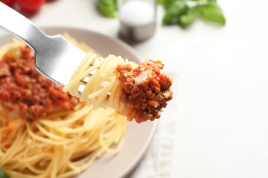 Photo of Fork with delicious pasta bolognese over table, closeup