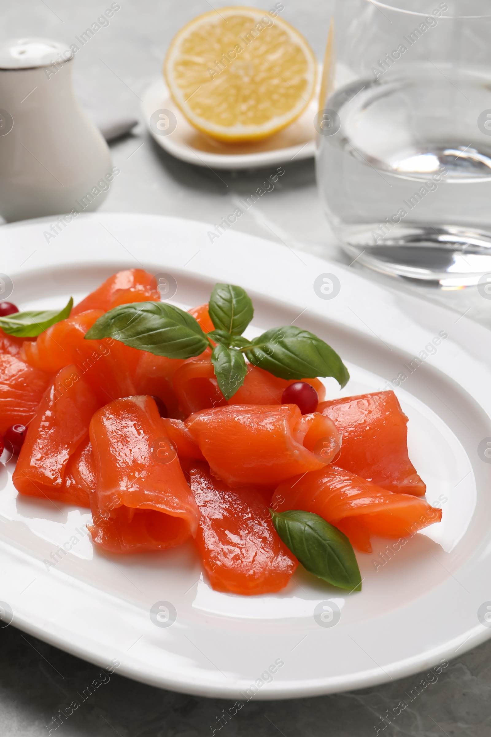 Photo of Salmon carpaccio with cranberries and basil served on table, closeup