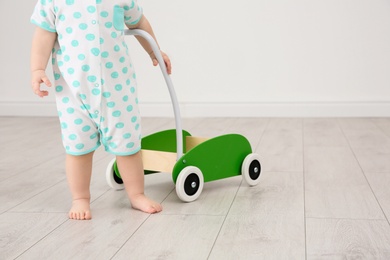 Cute baby playing with toy walker indoors, closeup