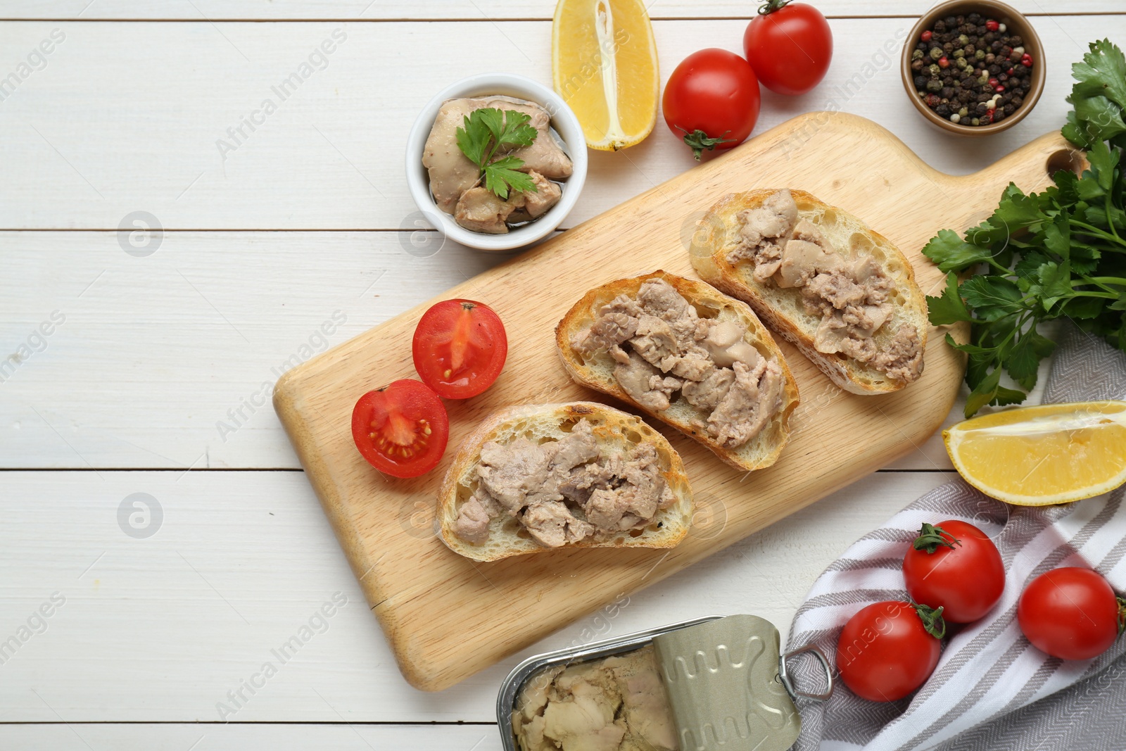 Photo of Tasty sandwiches with cod liver on white wooden table, flat lay. Space for text