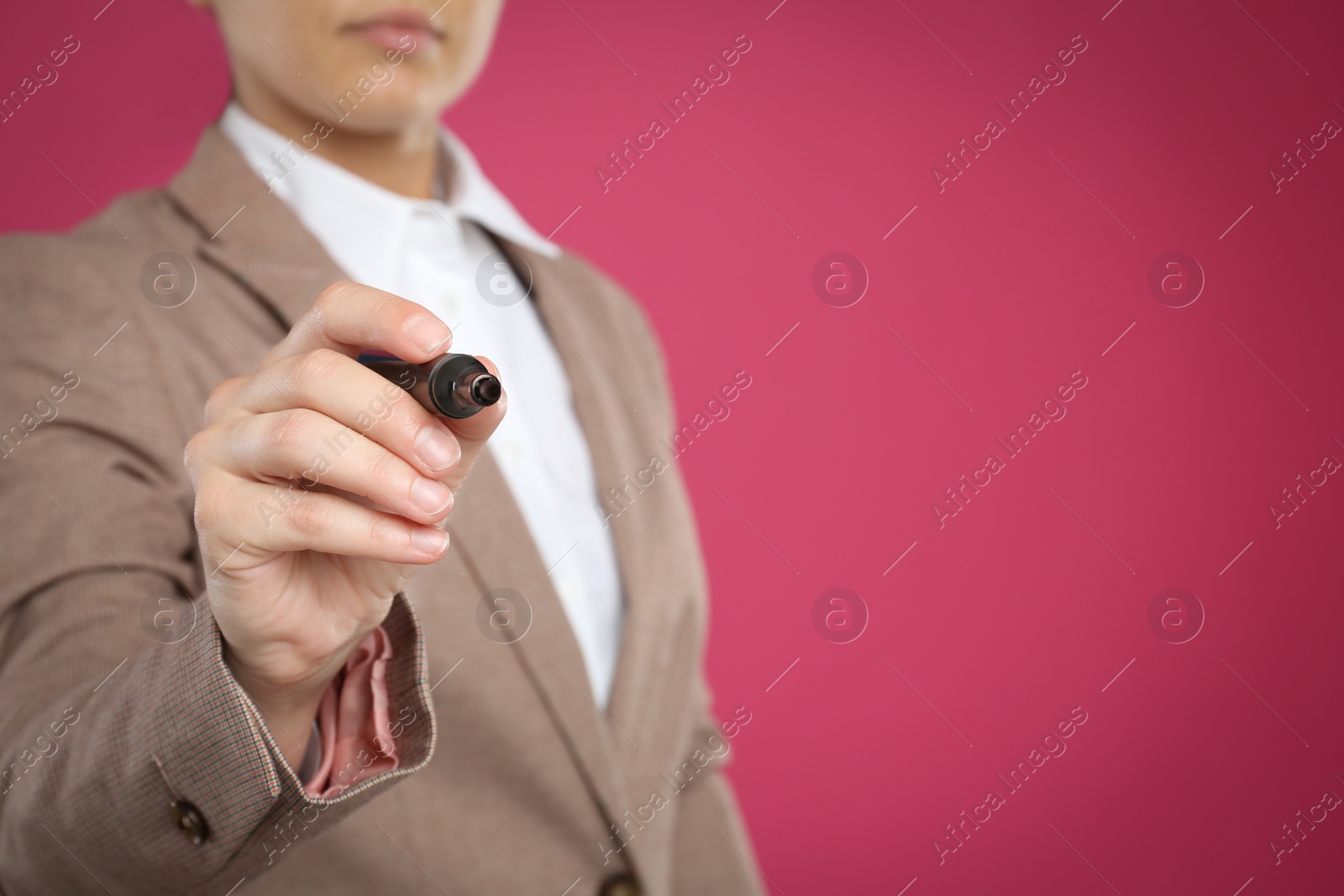 Photo of Woman with marker against pink background, focus on hand. Space for text
