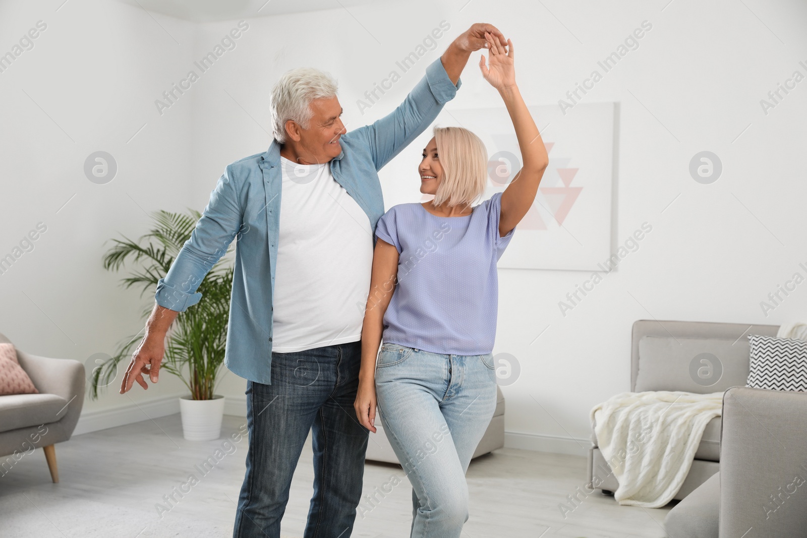 Photo of Happy mature couple dancing together in living room