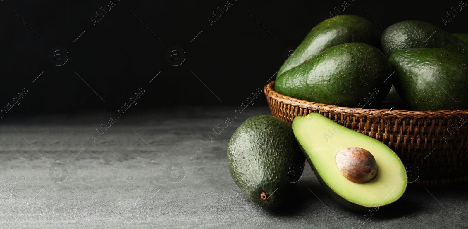 Image of Ripe avocados on grey table against dark background, space for text. Banner design