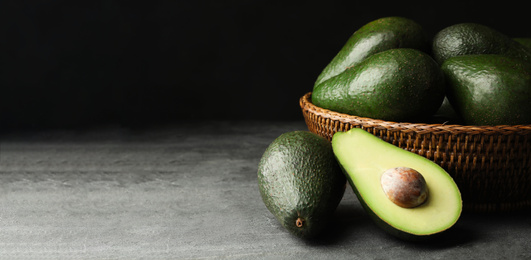 Image of Ripe avocados on grey table against dark background, space for text. Banner design