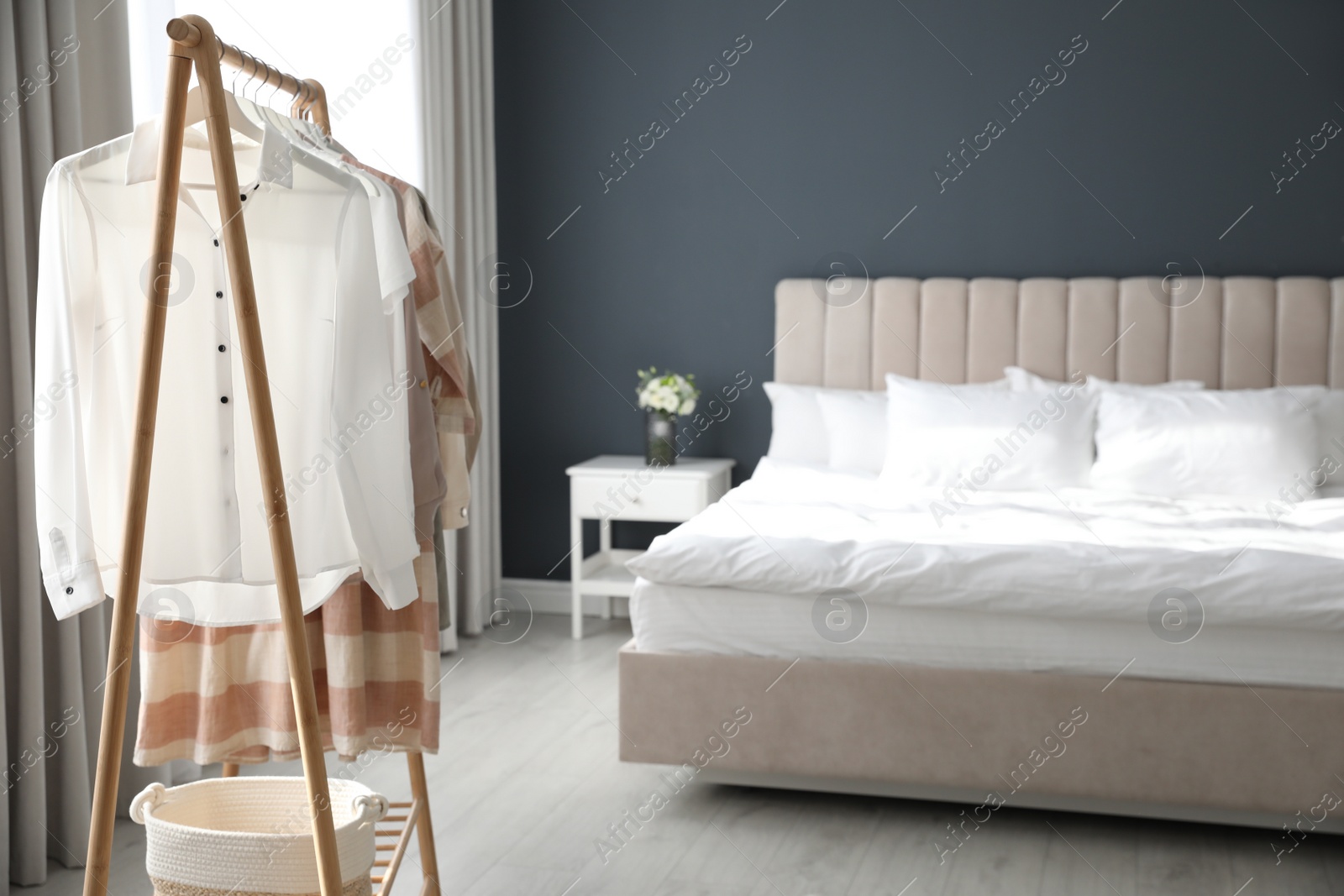 Photo of Different stylish clothes on rack in room