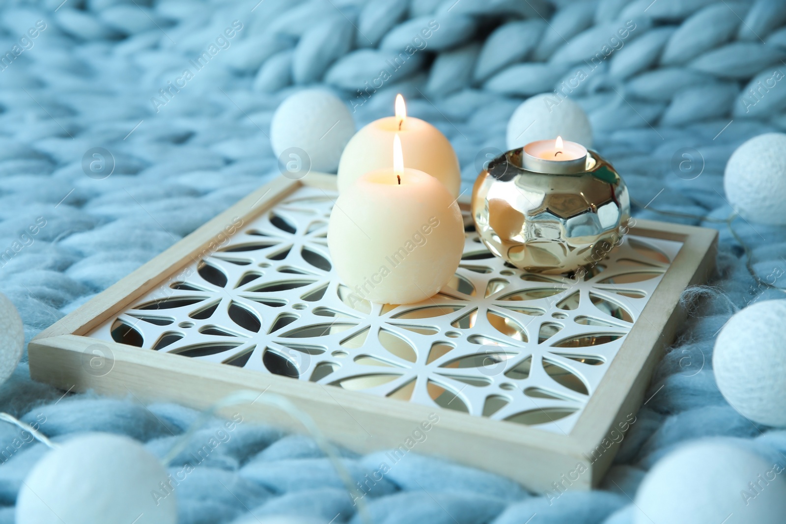 Photo of Burning candles and decor on knitted plaid