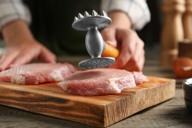 Photo of Woman cooking schnitzel at wooden table, selective focus