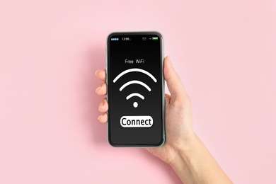Image of Woman connecting to WiFi using mobile phone on pink background, closeup