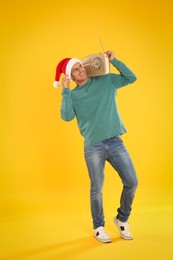 Photo of Happy man with vintage radio on yellow background. Christmas music