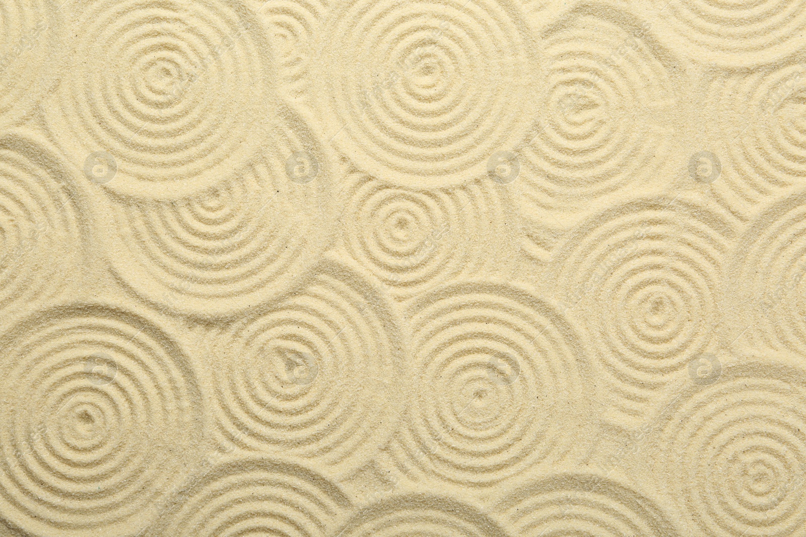 Photo of Zen rock garden. Circle patterns on beige sand, top view