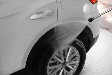Washing auto with high pressure water jet at outdoor car wash, closeup