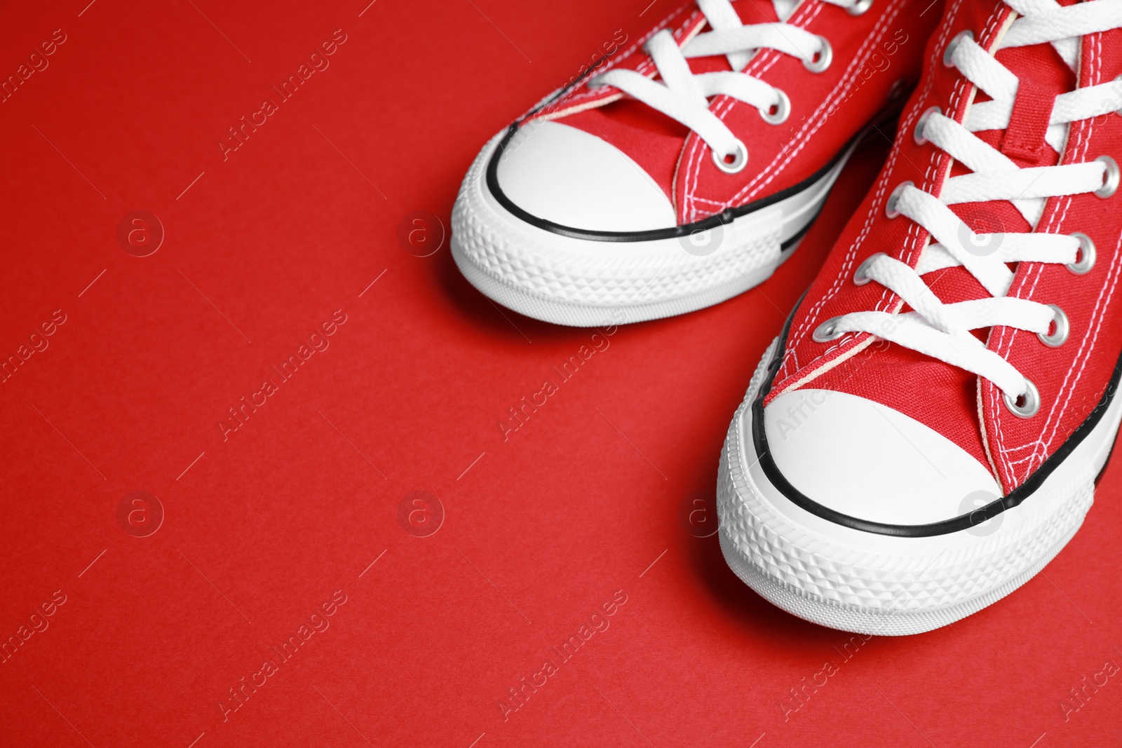 Photo of Pair of new stylish sneakers on red background, closeup. Space for text