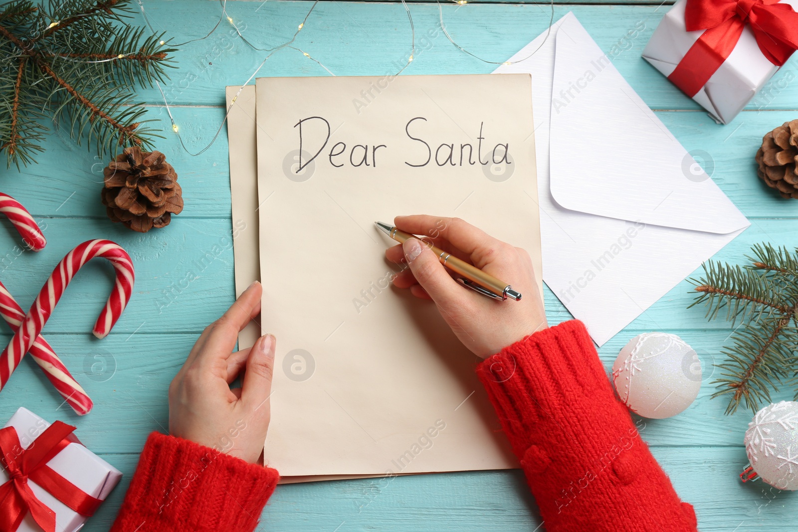 Photo of Woman writing letter to Santa at turquoise wooden table, top view