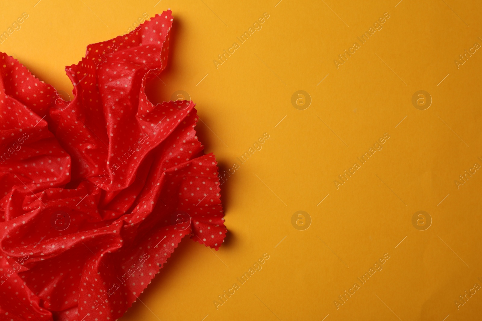 Photo of Crumpled beeswax food wrap on yellow background, top view. Space for text