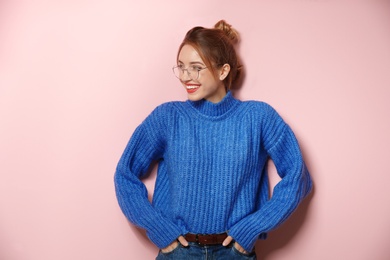 Beautiful young woman in warm sweater on color background