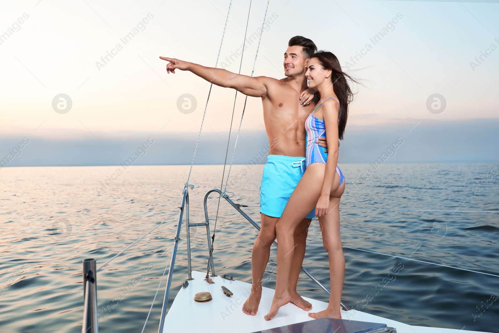 Photo of Young man and his beautiful girlfriend in bikini on yacht. Happy couple during sea trip