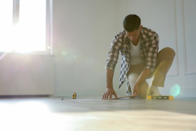 Professional worker installing new parquet flooring indoors