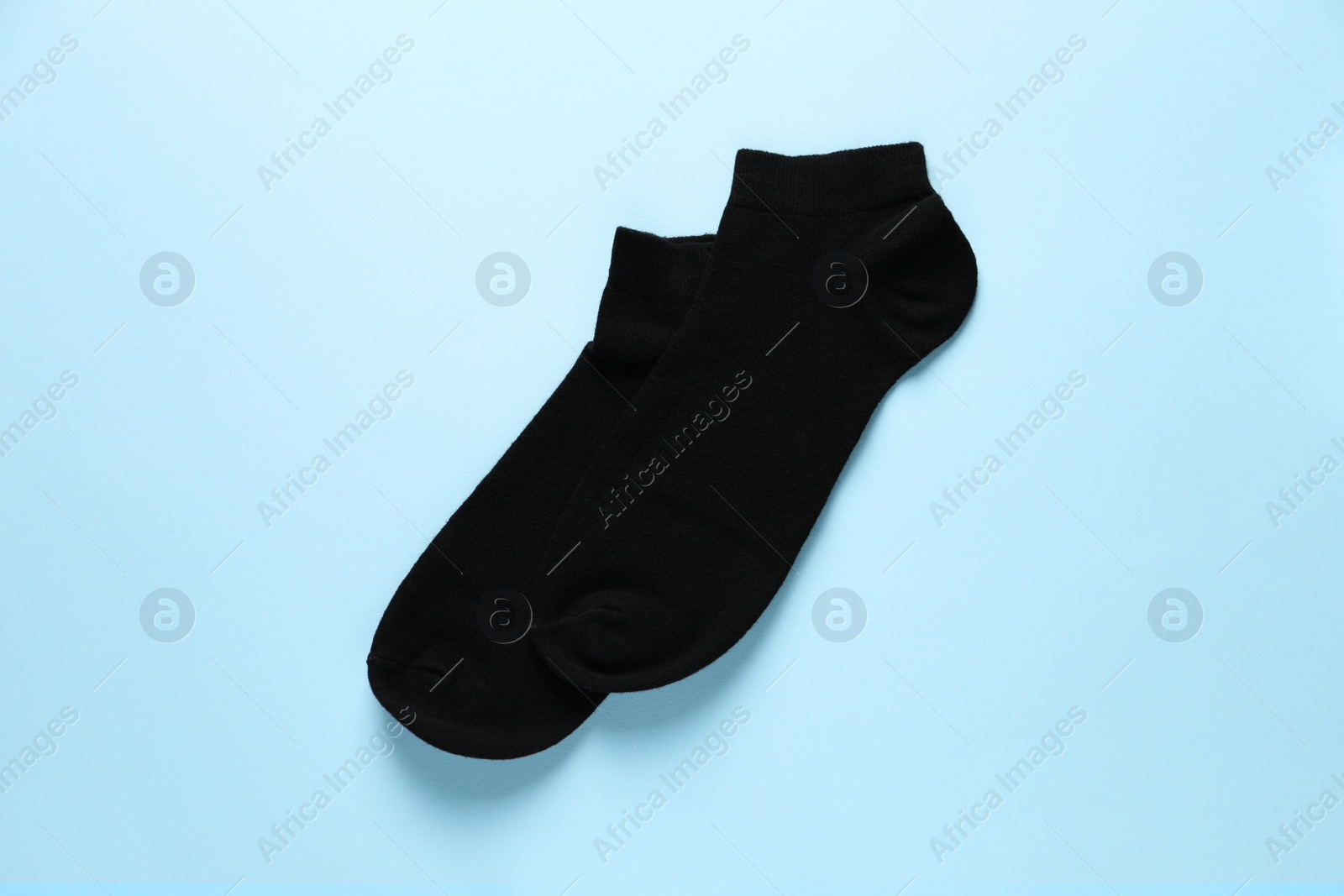 Photo of Pair of black socks on light blue background, flat lay
