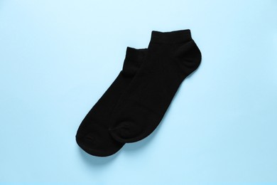 Pair of black socks on light blue background, flat lay